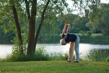 Seniorin beim Yoga am See